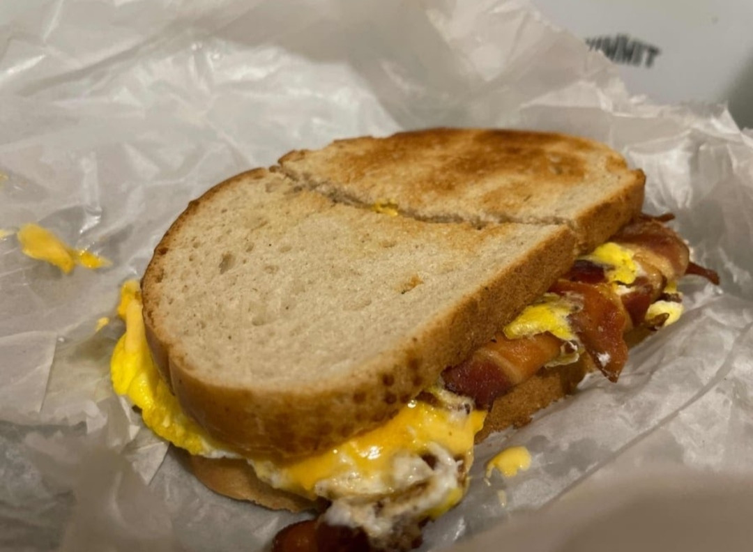 This image showcases a hearty breakfast sandwich from Crosstown Diner in the Bronx. The sandwich features perfectly toasted bread with layers of crispy bacon, melted cheese, and a well-cooked egg, making it a satisfying choice for a morning meal. Crosstown Diner is known for its fresh ingredients and generous portions, ensuring that every bite is delicious and fulfilling.